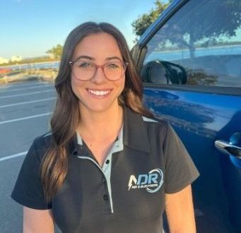 Carly beside a work vehicle