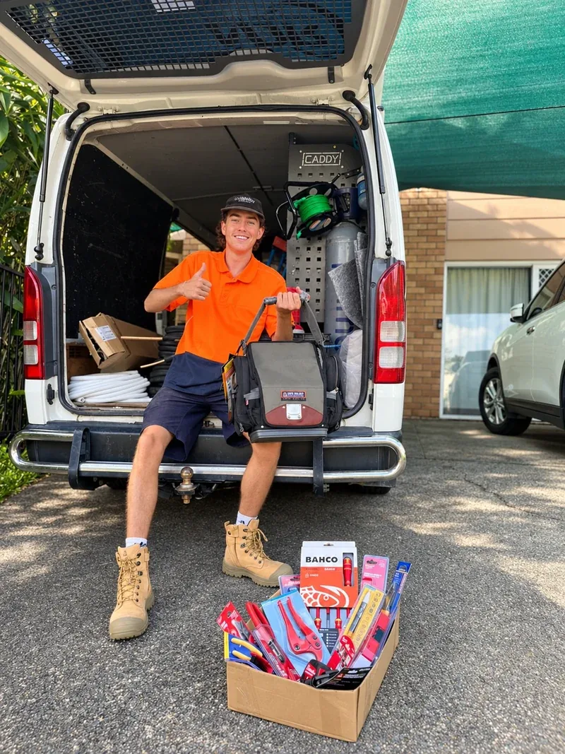 A technician with a tool bag at the back of a service van