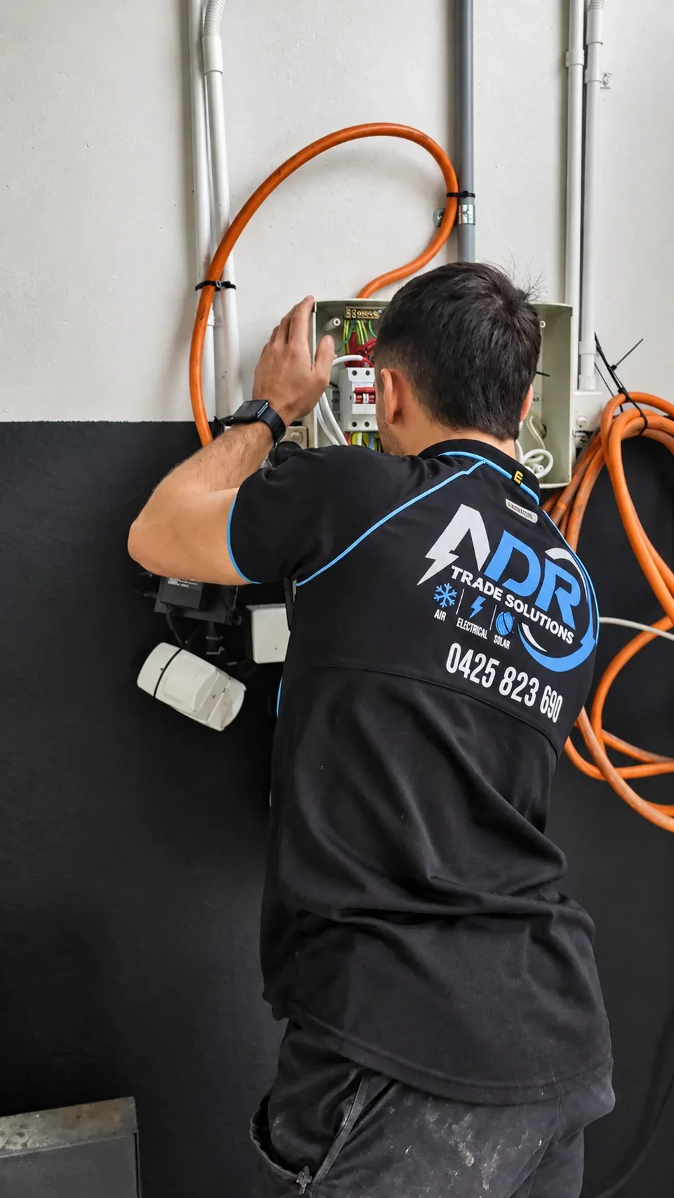 An NDR electrician working on an electrical panel